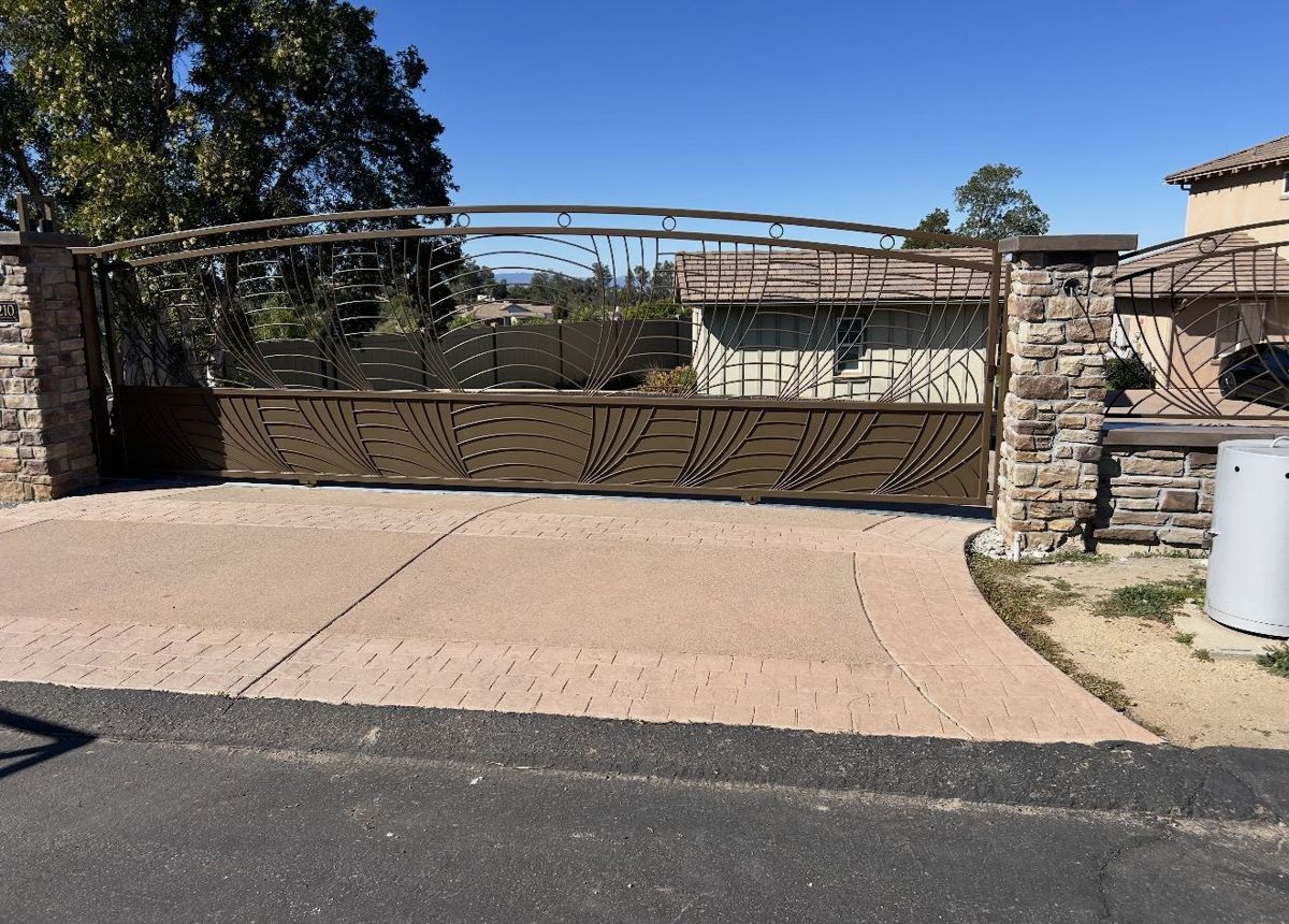 Custom bronze sliding driveway gate between stone pillars