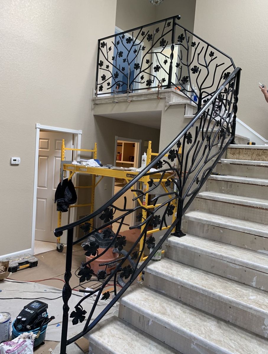 Interior wrought-iron staircase railing with hand-forged branches and leaves